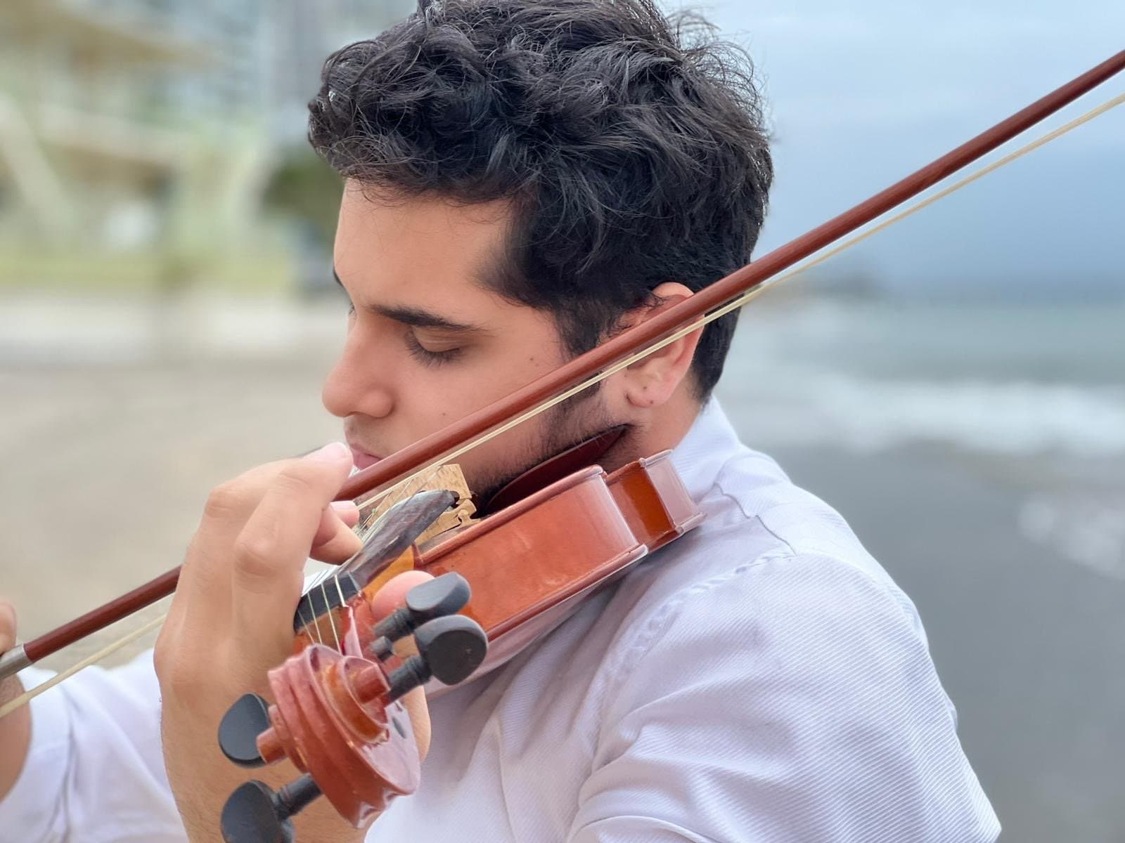 Raffael Figueroa toca el violín frente al mar